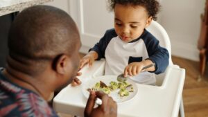 Toddler eating healthy food with parent support for strong teeth