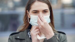 Person wearing a protective face mask outdoors to shield skin from pollution.