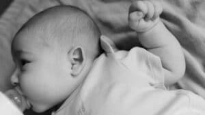 Newborn baby lying on its side while feeding from a bottle.