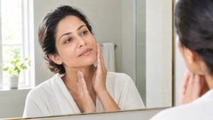Woman checking the skin on her cheek and neck in a mirror — Profhilo skin hydration and firmness, Pandit Clinic, Pune